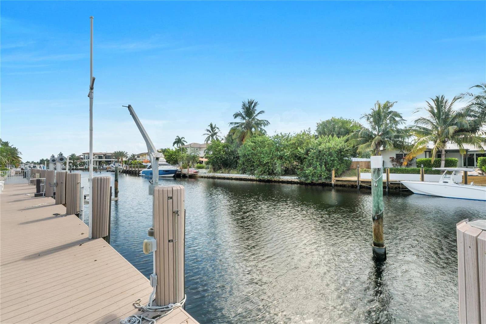 A wooden boat dock overlooks a canal with moored boats and palm trees — 4020 NE 24th Avenue, Lighthouse Point FL 33064, LIGHTHOUSE POINT, FL