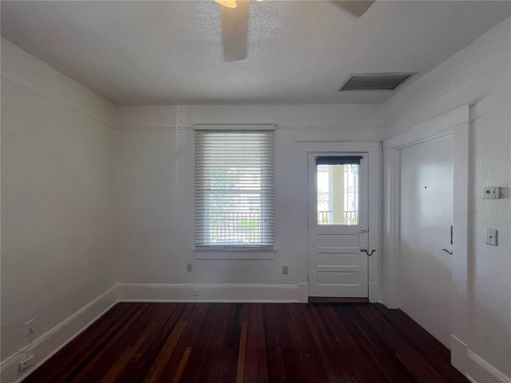 A room with white walls, dark wood flooring, a window with blinds, and a door — 429 RUTH LN UNIT 4, ORLANDO, FL