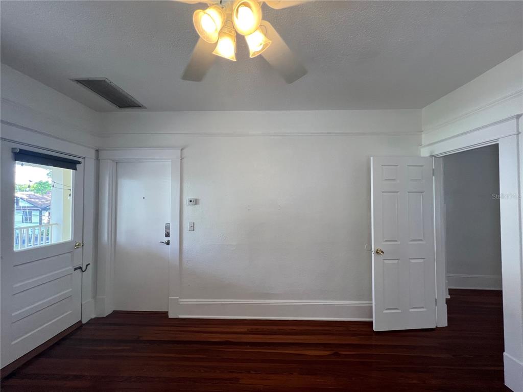A room with hardwood floors, white walls, a ceiling fan, and three white doors — 429 RUTH LN UNIT 4, ORLANDO, FL
