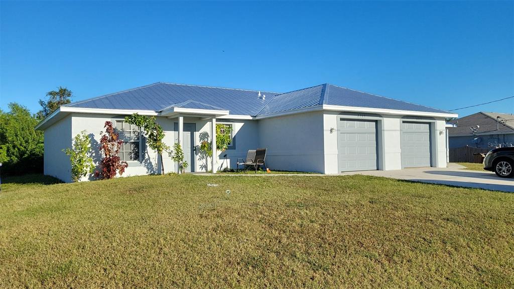 A single-story house with a metal roof, two garage doors, and a front lawn — 2209/2211 DANIEL AVENUE N, LEHIGH ACRES, FL