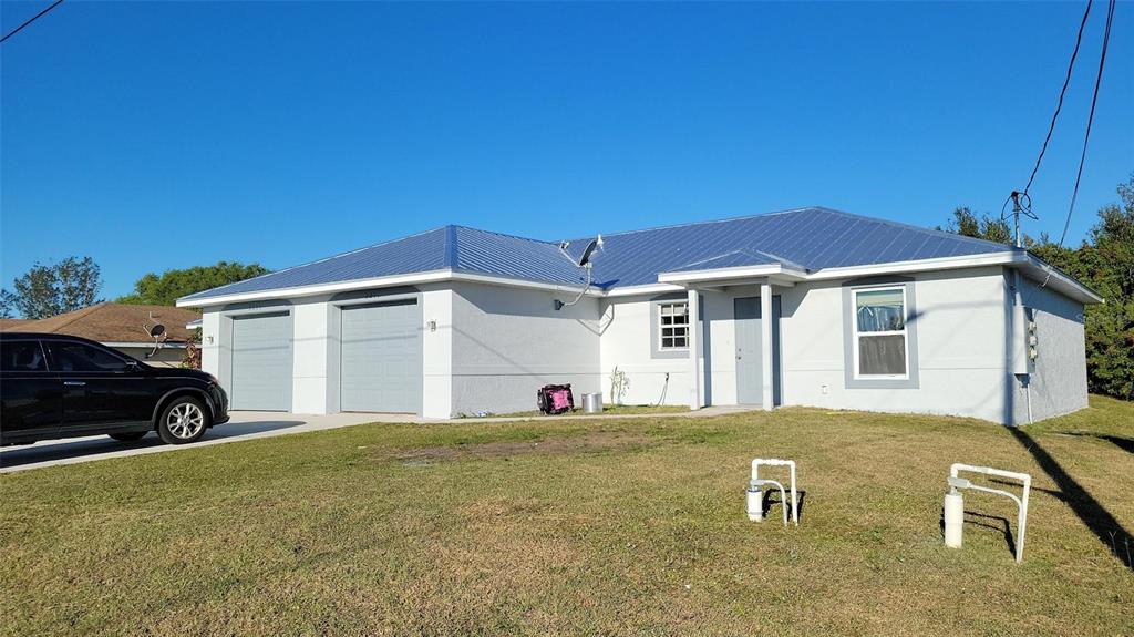 A single-story house with a metal roof, two garage doors, and a front entrance — 2209/2211 DANIEL AVENUE N, LEHIGH ACRES, FL