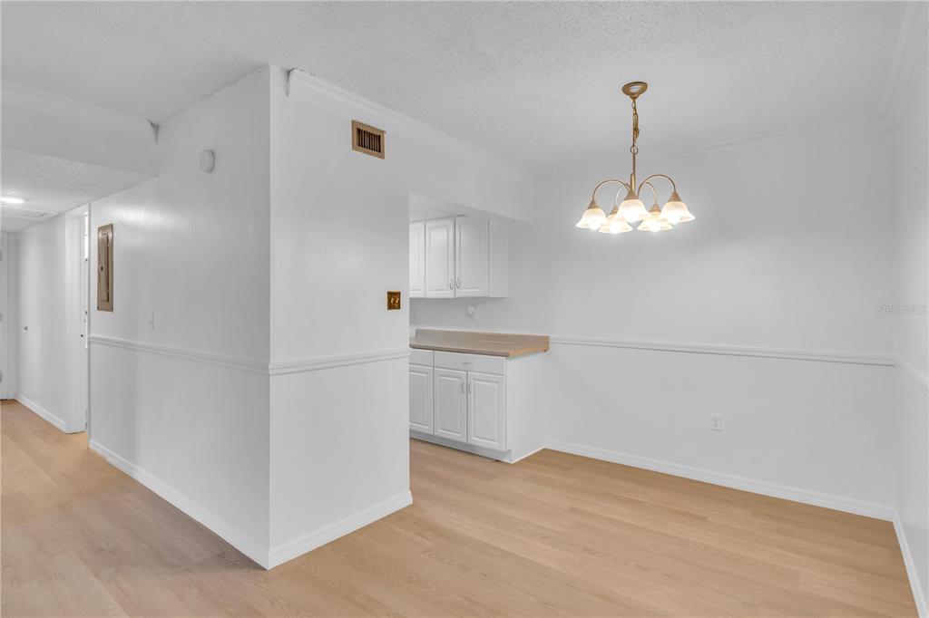 A dining area with light wood flooring, white walls, and a hanging chandelier — 916 LAKE DESTINY ROAD UNIT E, ALTAMONTE SPRINGS, FL