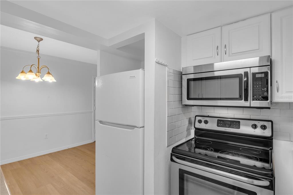 A kitchen with white cabinets, stainless steel appliances, and a view into a dining area — 916 LAKE DESTINY ROAD UNIT E, ALTAMONTE SPRINGS, FL