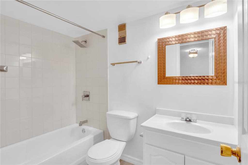 A bathroom features a white vanity, a toilet, and a shower-tub combination with tiled walls — 916 LAKE DESTINY ROAD UNIT E, ALTAMONTE SPRINGS, FL