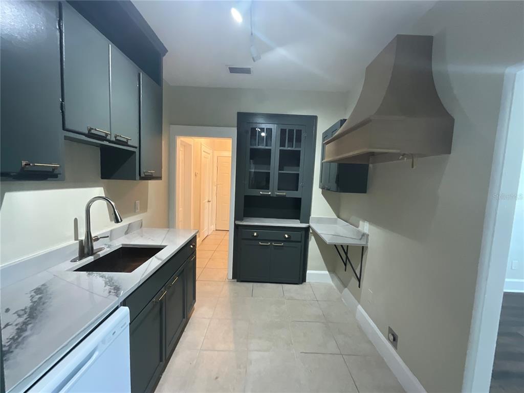 A kitchen features dark cabinets, marble-look countertops, a farmhouse sink, and a range hood — 2610 CENTRAL AVENUE UNIT 1, ST PETERSBURG, FL