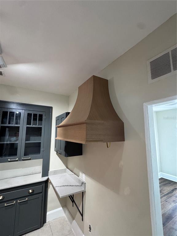 A kitchen features a wooden range hood, dark gray cabinets, and a small stone counter — 2610 CENTRAL AVENUE UNIT 1, ST PETERSBURG, FL