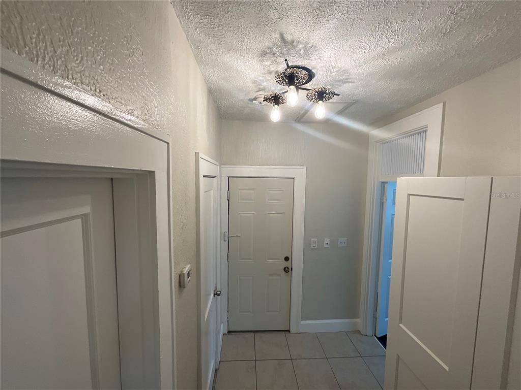 A hallway with tiled flooring, white doors, and a three-bulb ceiling light fixture — 2610 CENTRAL AVENUE UNIT 1, ST PETERSBURG, FL