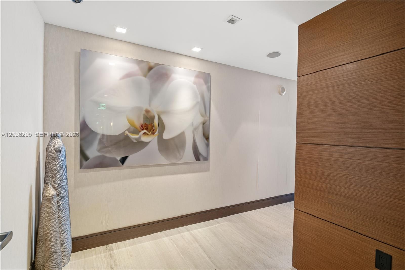 A hallway features a large orchid print, a textured floor vase, and wood-paneled walls — 465 Brickell Ave # 2101, Miami FL 33131, MIAMI, FL