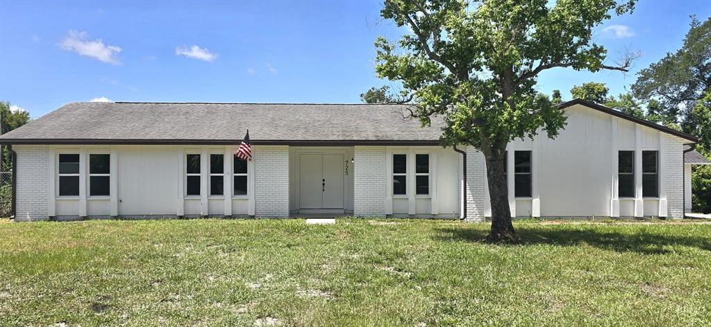 A single-story white house with a brick facade and a large tree in front — 725 TULIP COURT, DELTONA, FL