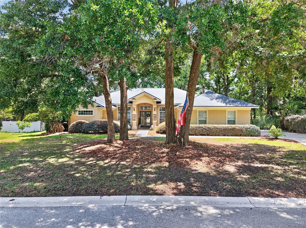 A single-story house with a tan exterior, a front porch, and large trees in front — 4525 SE 48TH PLACE ROAD, OCALA, FL