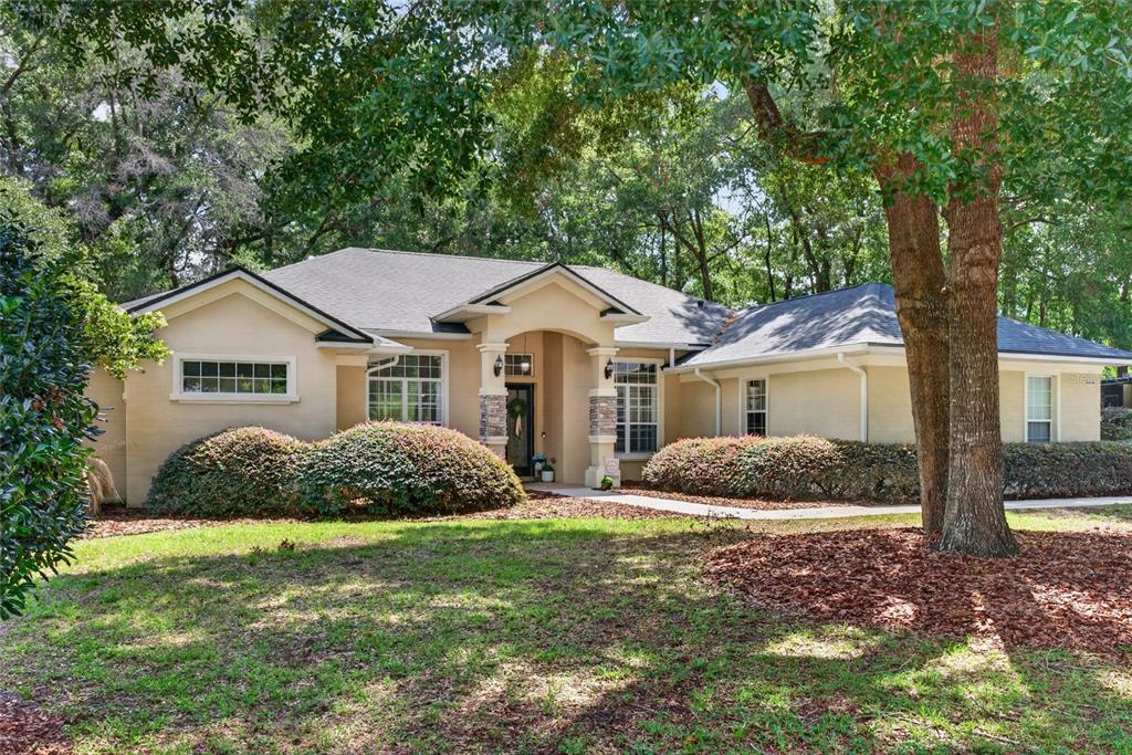 A single-story beige house with a stone-accented entryway and a large tree in front — 4525 SE 48TH PLACE ROAD, OCALA, FL
