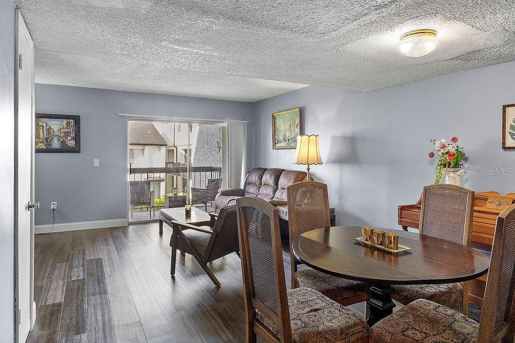 A living and dining area features light blue walls, wood-look flooring, and a sliding glass door — 4269 S SEMORAN BOULEVARD UNIT 14, ORLANDO, FL