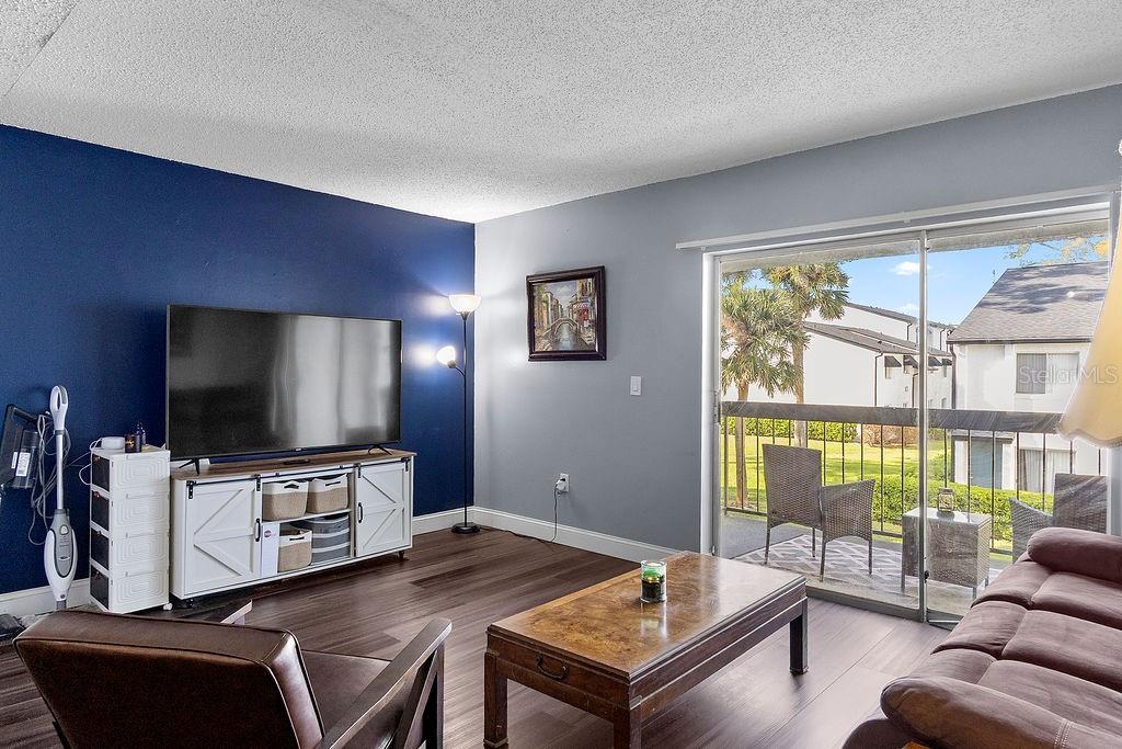 A living room features a blue accent wall, dark wood floors, and a sliding glass door — 4269 S SEMORAN BOULEVARD UNIT 14, ORLANDO, FL