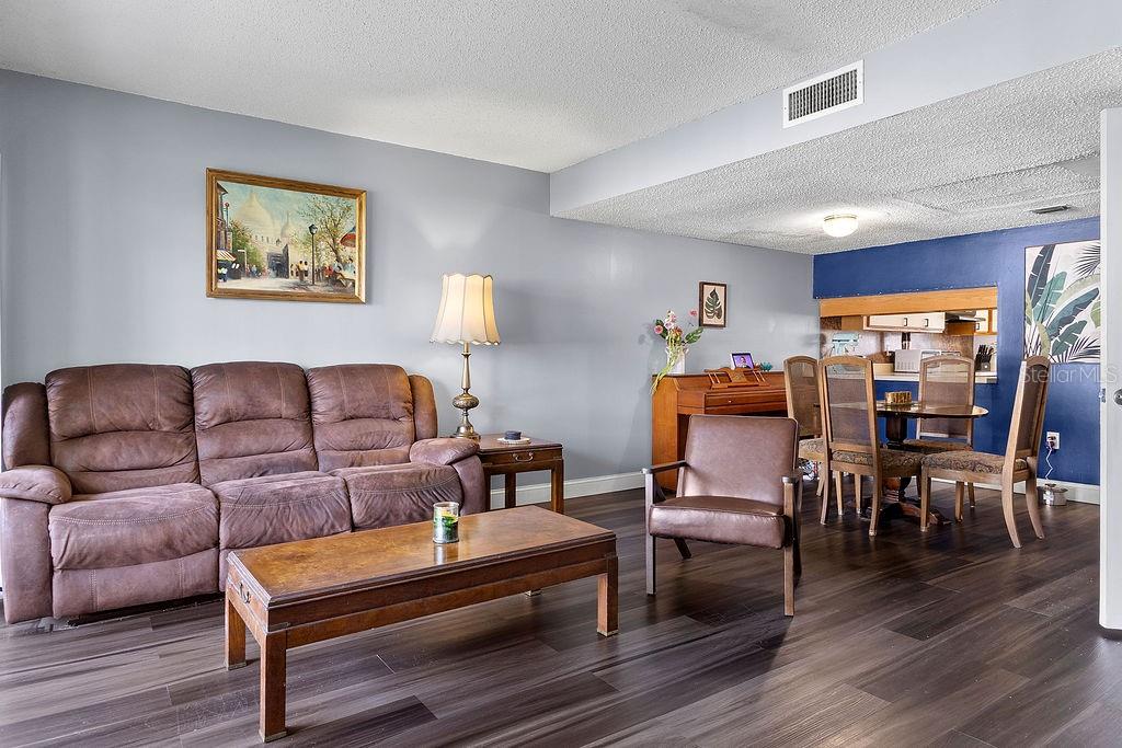 A living room and dining area with brown furniture, wood-look flooring, and blue accent walls — 4269 S SEMORAN BOULEVARD UNIT 14, ORLANDO, FL