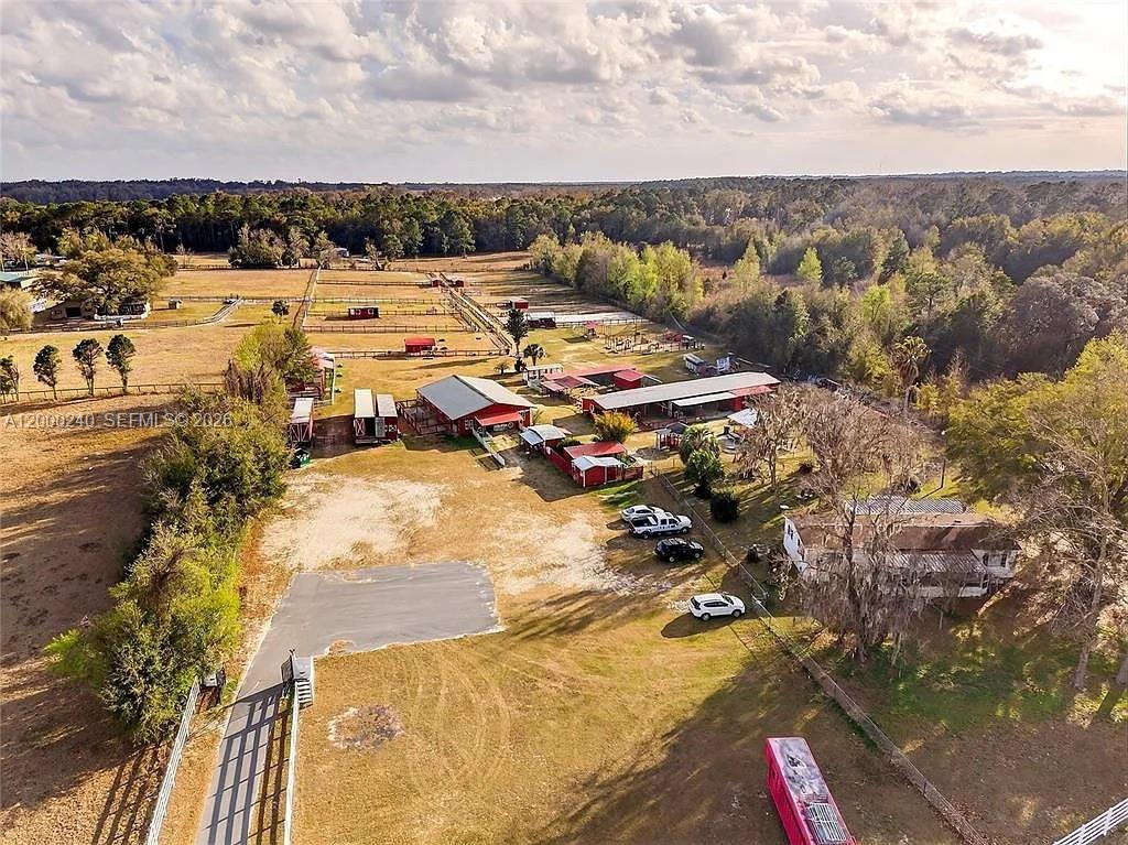 An aerial view shows a rural property with multiple red barns, fenced pastures, and a house — 11150 W Highway 40, Ocala FL 34482-6840, OCALA, FL