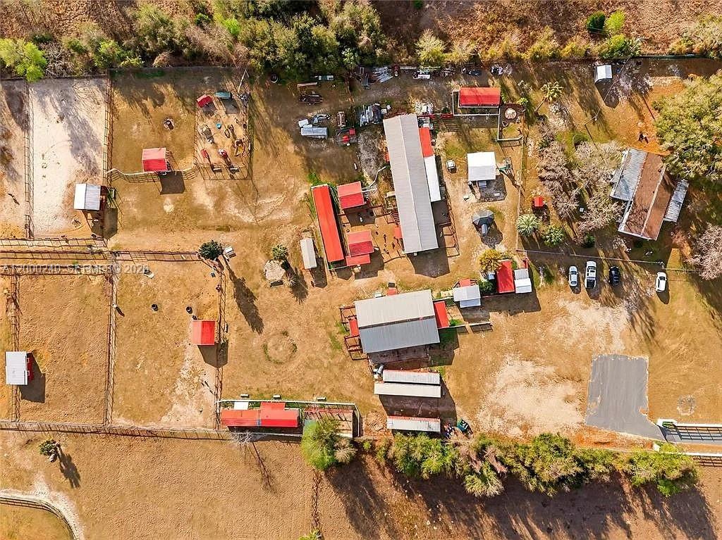 An aerial view shows a rural property with multiple barns, fenced paddocks, and a house — 11150 W Highway 40, Ocala FL 34482-6840, OCALA, FL