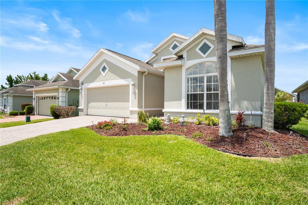 A single-story suburban house with a beige stucco exterior, a two-car garage, and palm trees — 223 RIDGE VIEW DRIVE, DAVENPORT, FL