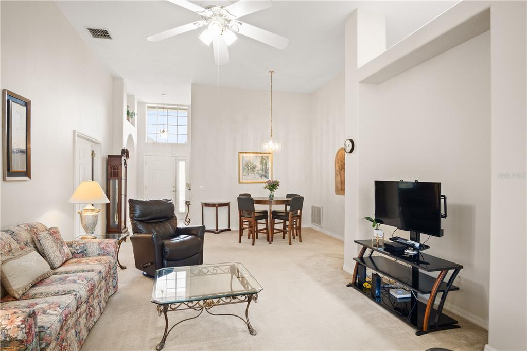 A living and dining area with high ceilings, beige carpeting, and neutral-colored walls — 223 RIDGE VIEW DRIVE, DAVENPORT, FL