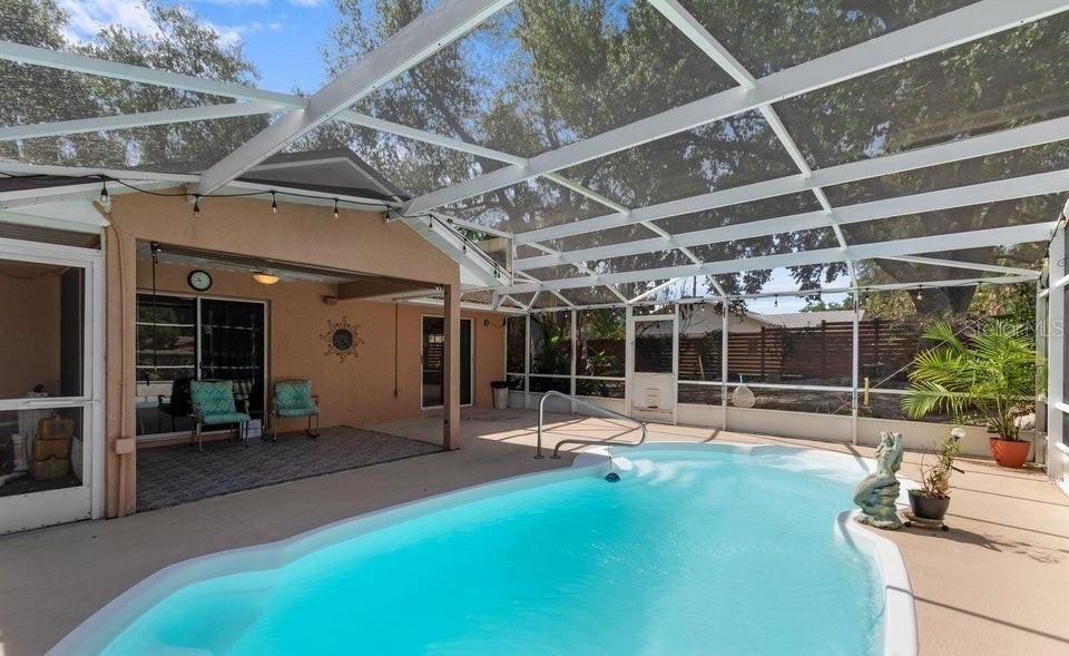 A screened-in patio features a swimming pool, a covered seating area, and a fenced backyard — 10825 BEVERLY COURT, CLERMONT, FL