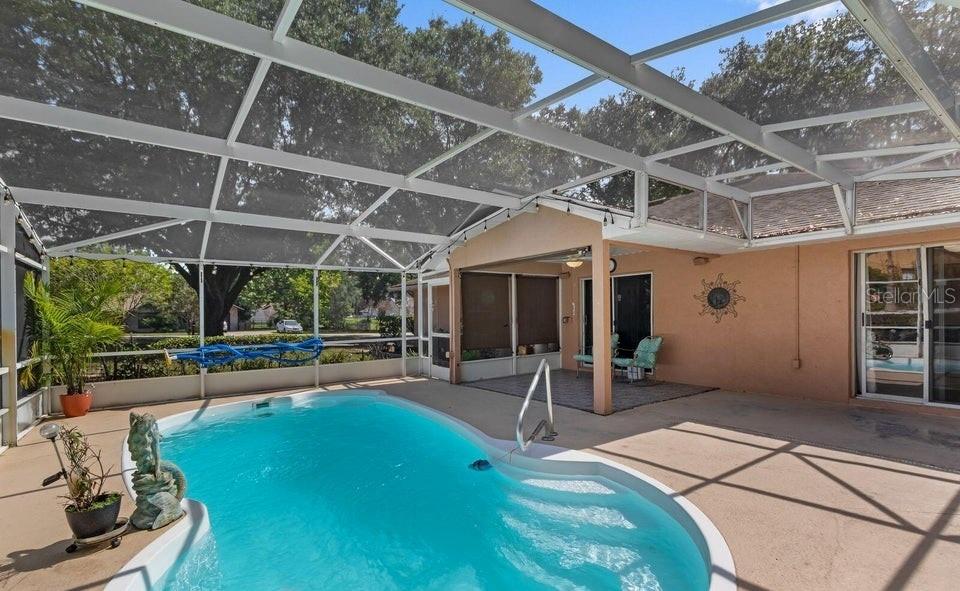 A screened-in patio features a kidney-shaped swimming pool and a covered seating area — 10825 BEVERLY COURT, CLERMONT, FL