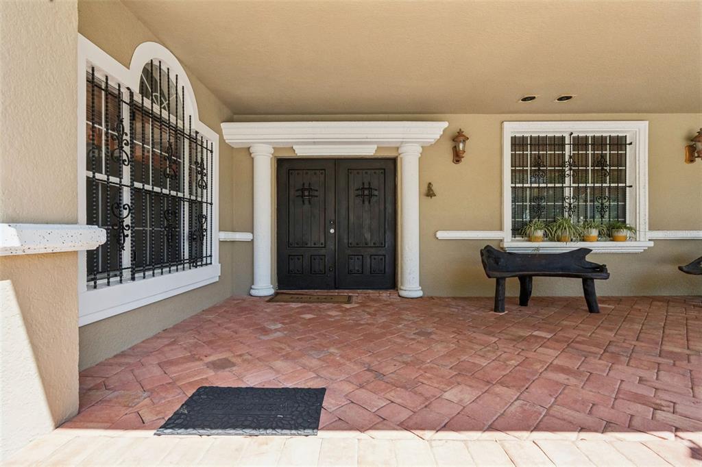 A covered porch features a brick floor, double front doors, and windows with security bars — 5825 LAKE LIZZIE DRIVE, ST CLOUD, FL