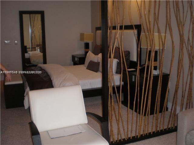 A bedroom features a bed, a white armchair, and a decorative bamboo room divider — 5300 NW 87 Avenue # 406, Doral FL 33178, DORAL, FL
