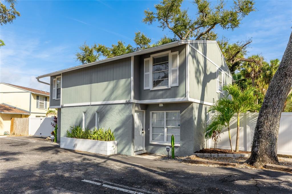 A two-story gray house with a white door, horizontal siding, and a small front garden — 1610 & 1612 N ORANGE AVENUE, SARASOTA, FL