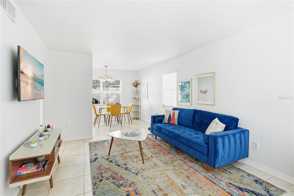 A living room with a blue sofa, a patterned rug, and an adjacent dining area — 1610 & 1612 N ORANGE AVENUE, SARASOTA, FL