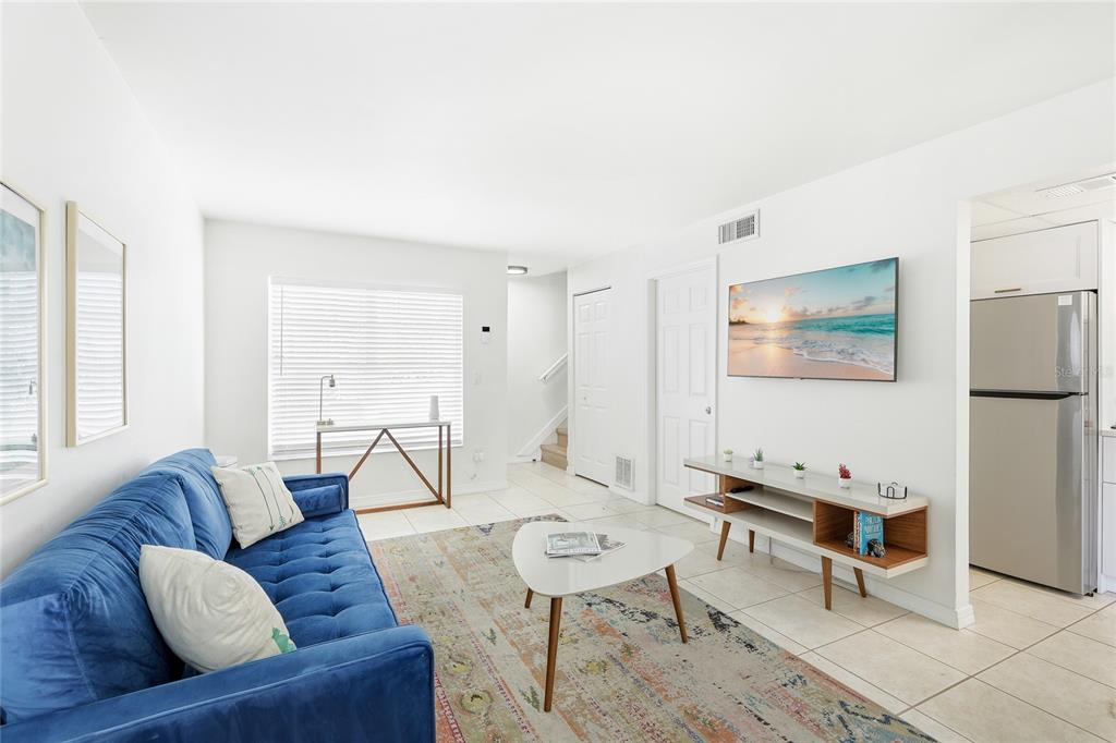 A living room features a blue tufted sofa, a patterned rug, and a wall-mounted television — 1610 & 1612 N ORANGE AVENUE, SARASOTA, FL