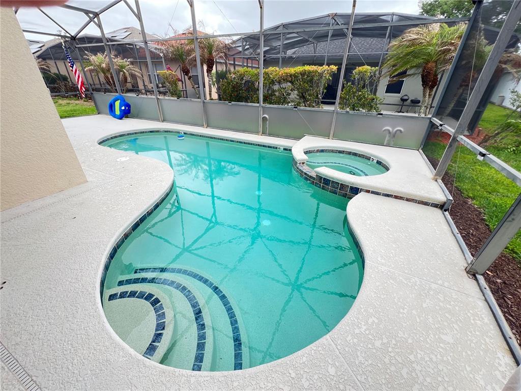 A screened-in swimming pool and attached hot tub sit on a concrete patio — 176 MINNIEHAHA CIRCLE, HAINES CITY, FL