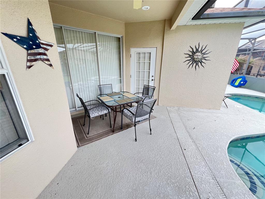 A covered patio features a dining set, a sliding glass door, and a swimming pool — 176 MINNIEHAHA CIRCLE, HAINES CITY, FL