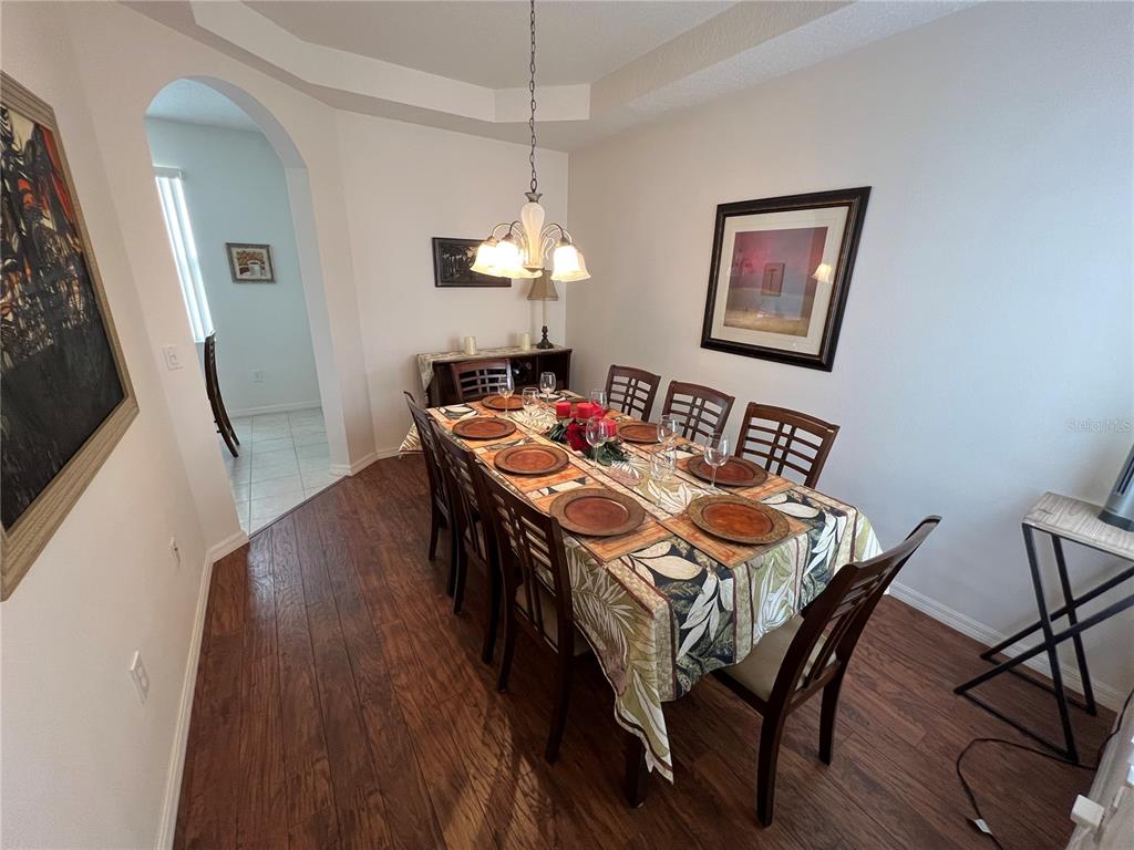 A dining room features a wooden table with six chairs, a chandelier, and hardwood floors — 176 MINNIEHAHA CIRCLE, HAINES CITY, FL