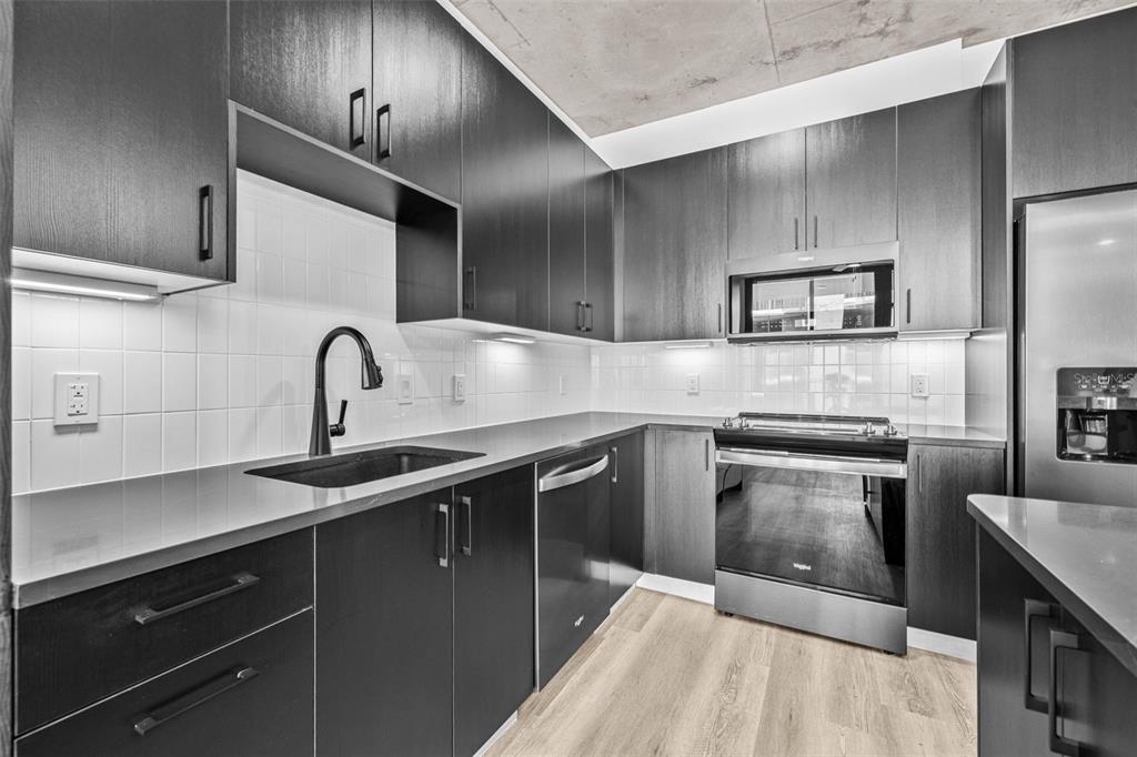 A modern kitchen features dark wood cabinetry, stainless steel appliances, and light wood flooring — 221 MAIN STREET N UNIT A2-1102, ST PETERSBURG, FL