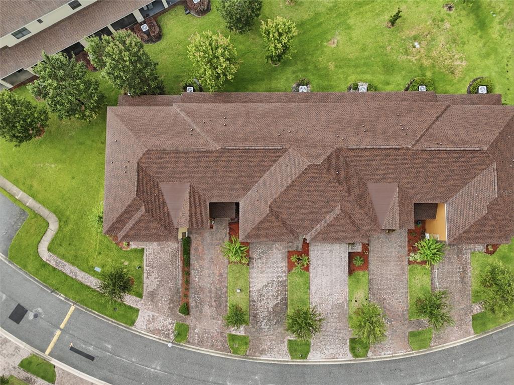 An aerial view shows the brown shingled roof and brick driveways of a multi-unit townhouse — 1940 PORTOFINO MEADOWS BOULEVARD, ORLANDO, FL