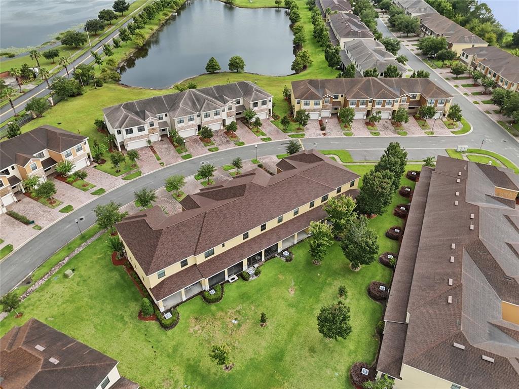 An aerial view shows multiple multi-family residential buildings surrounded by green lawns and a pond — 1940 PORTOFINO MEADOWS BOULEVARD, ORLANDO, FL