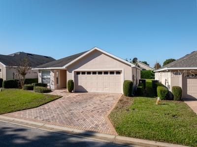 A single-story house with a beige exterior, a two-car garage, and a brick-paved driveway — 3865 OSPREY POINTE CIRCLE, WINTER HAVEN, FL