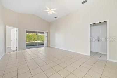 An empty room with light tile flooring, a vaulted ceiling, and sliding glass patio doors — 3865 OSPREY POINTE CIRCLE, WINTER HAVEN, FL