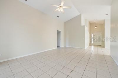 An empty room with light-colored tile flooring, a vaulted ceiling, and a ceiling fan — 3865 OSPREY POINTE CIRCLE, WINTER HAVEN, FL