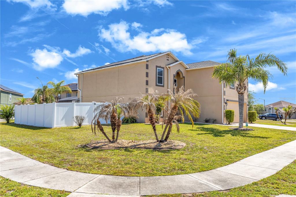 A two-story tan stucco house with a white vinyl fence and palm trees — 1874 CORNER MEADOW CIRCLE, ORLANDO, FL