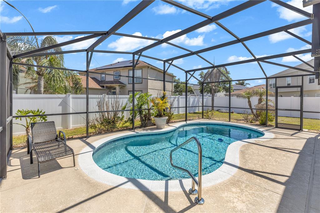 A screened-in patio features a kidney-shaped swimming pool with a metal handrail and lounge chair — 1874 CORNER MEADOW CIRCLE, ORLANDO, FL