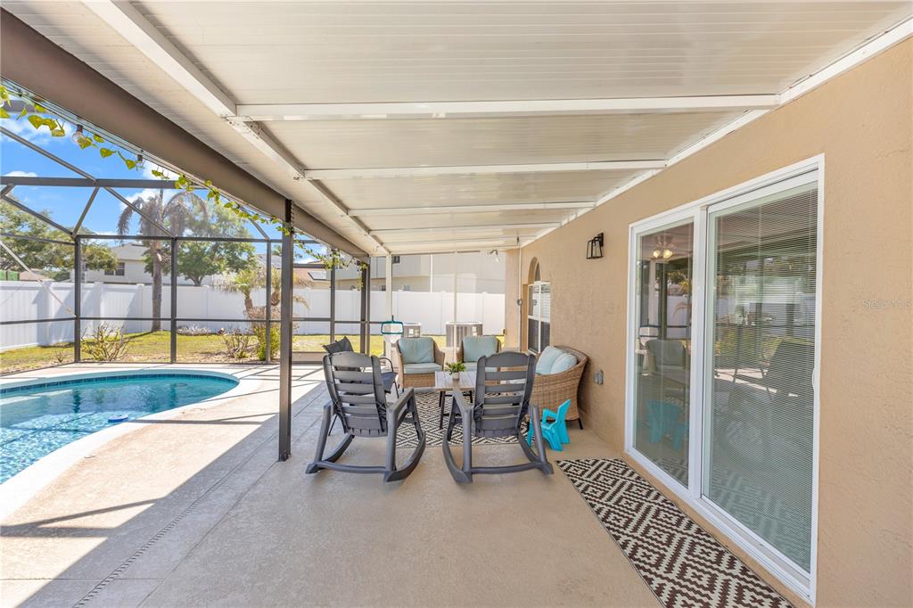 A covered patio features a swimming pool, outdoor furniture, and sliding glass doors — 1874 CORNER MEADOW CIRCLE, ORLANDO, FL