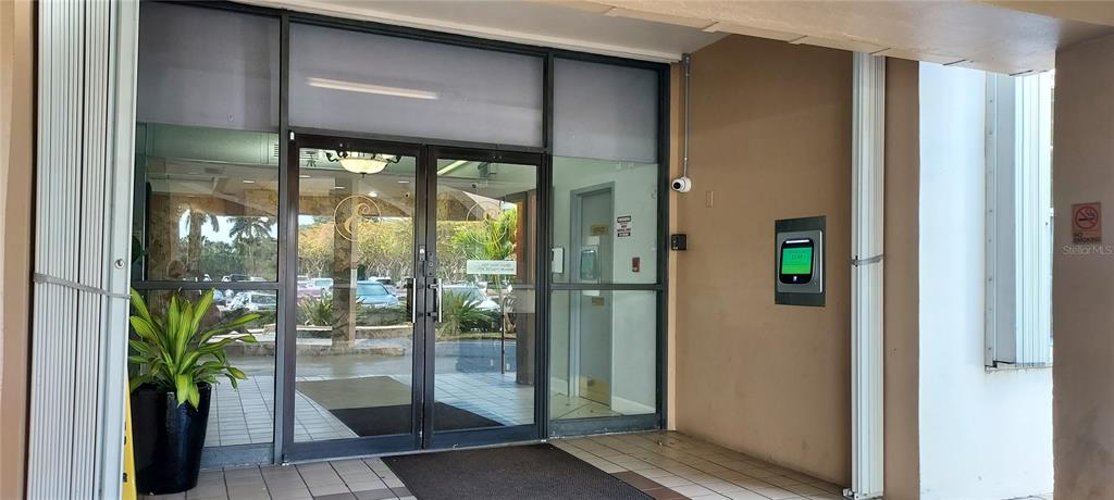 A glass-fronted building entrance features a security keypad and a potted plant — 1000 SAINT CHARLES PLACE UNIT 209, PEMBROKE PINES, FL