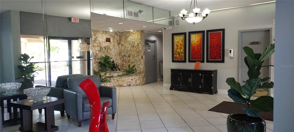 A lobby features tiled floors, a stone accent wall, a chandelier, and a seating area — 1000 SAINT CHARLES PLACE UNIT 209, PEMBROKE PINES, FL