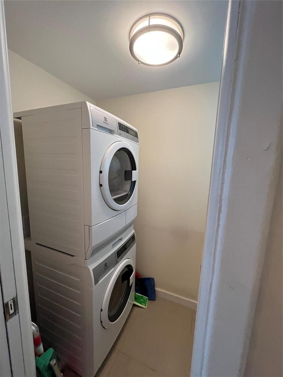A stacked washer and dryer unit sits in a small, white-walled laundry closet — 333 NE 21st Avenue # 318, Deerfield Beach FL 33441, DEERFIELD BEACH, FL