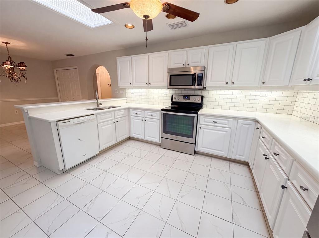 A kitchen with white cabinets, stainless steel appliances, a subway tile backsplash, and tiled flooring — 11540 CAMP DRIVE, DUNNELLON, FL