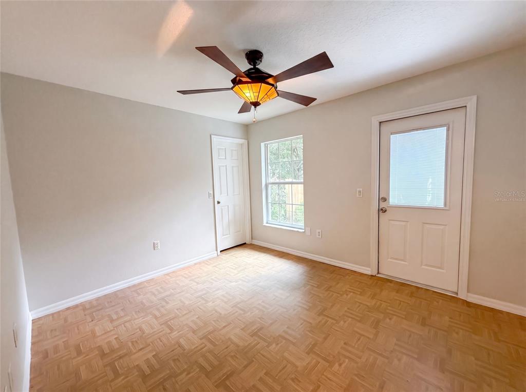 An empty room features light-colored walls, parquet wood flooring, a ceiling fan, and two doors — 11540 CAMP DRIVE, DUNNELLON, FL