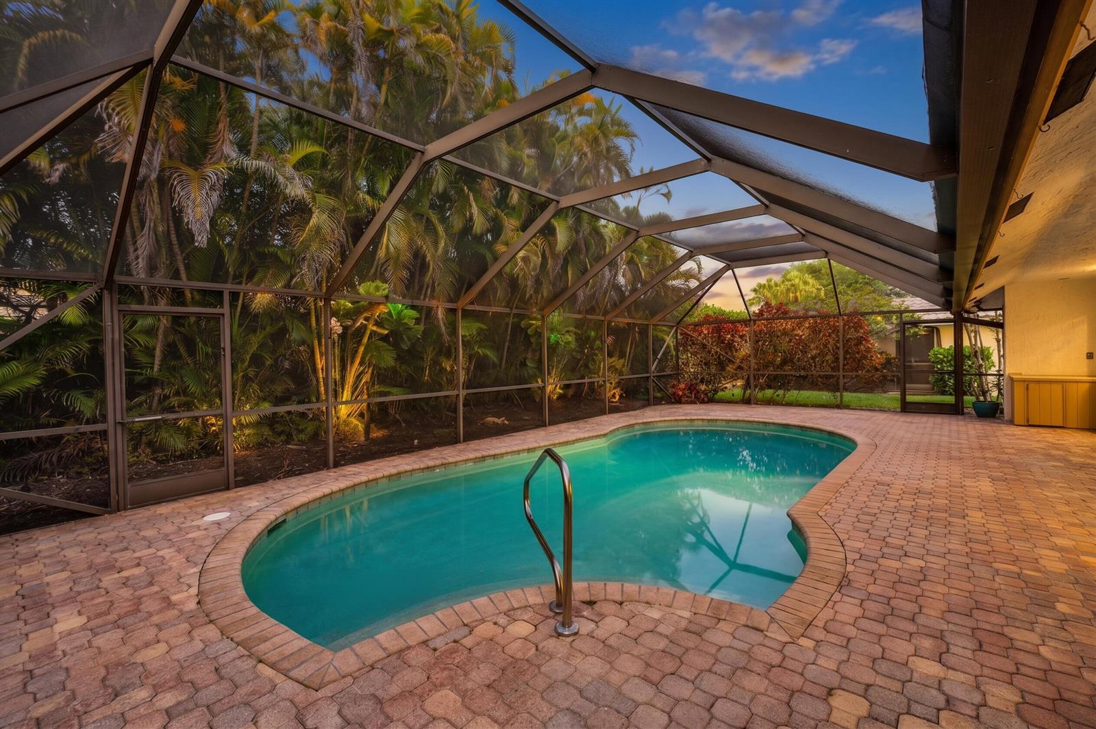 A screened-in swimming pool with a brick paver deck surrounded by lush tropical landscaping — 4382 White Cedar Lane, Delray Beach FL 33445, DELRAY BEACH, FL
