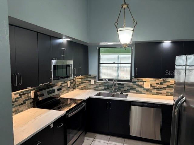 A kitchen features dark cabinets, stainless steel appliances, a tiled backsplash, and white countertops — 3514 NW 110TH TERRACE, GAINESVILLE, FL