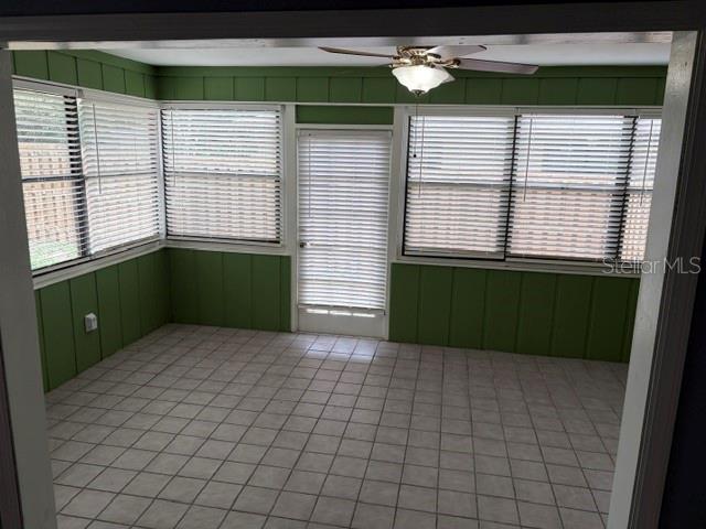 A sunroom with green paneled walls, tile flooring, a ceiling fan, and many window blinds — 3514 NW 110TH TERRACE, GAINESVILLE, FL