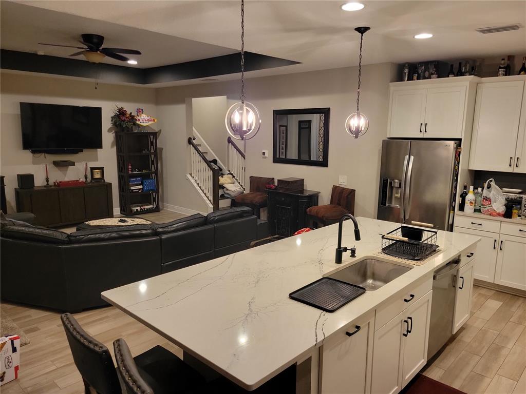 A kitchen with a large white quartz island overlooks a living room with a television — 12571 NIGHT VIEW DRIVE, SARASOTA, FL